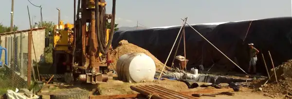 Water well drilling site with rig, water tank and sand pile